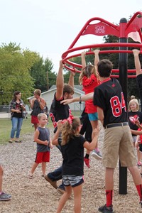 High school students playing with elementary students on playground