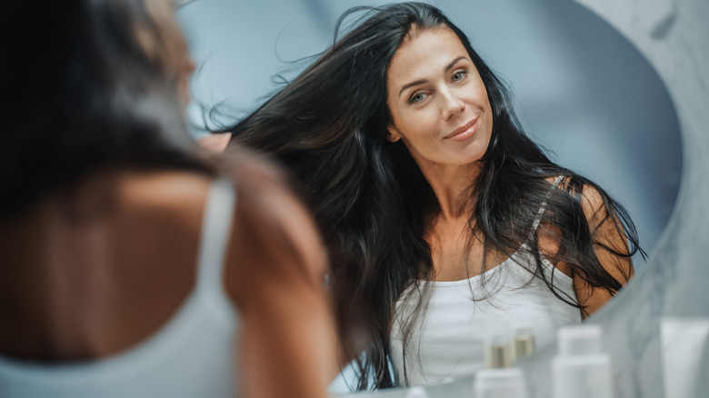 Woman with dark brunette hair looking in the mirror