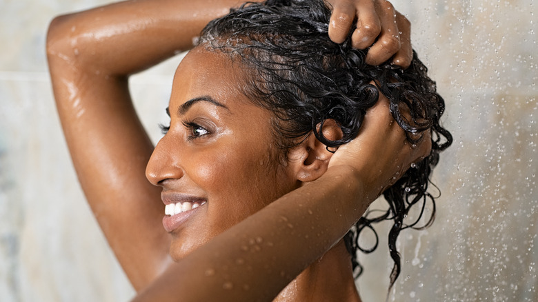 smiling woman washing hair under shower