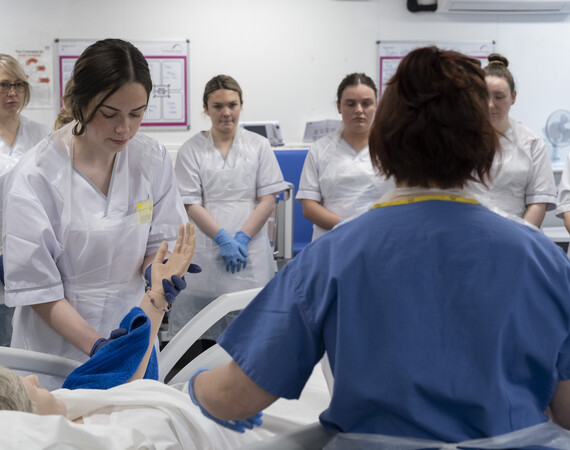 A healthcare student and lecturer working with a medical dummy.