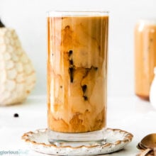 A glass of pumpkin cream cold brew on a decorative plate.