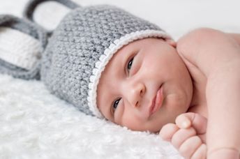 Cute newborn on a white blanket.