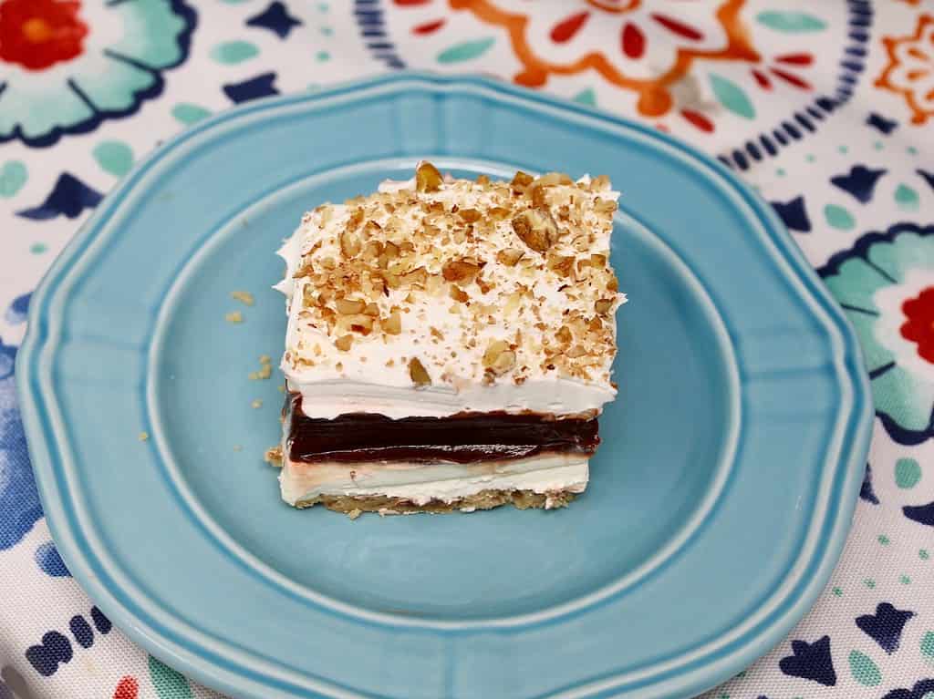 chocolate delight on a serving plate with chopped pecans decorating the top