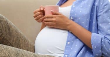 Young pregnant woman holding her tummy at home