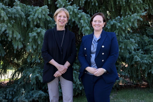 Vivian Schiller, on the left, stands next to Heather Adkins, on the right. They are pictured smiling in front of a tree.