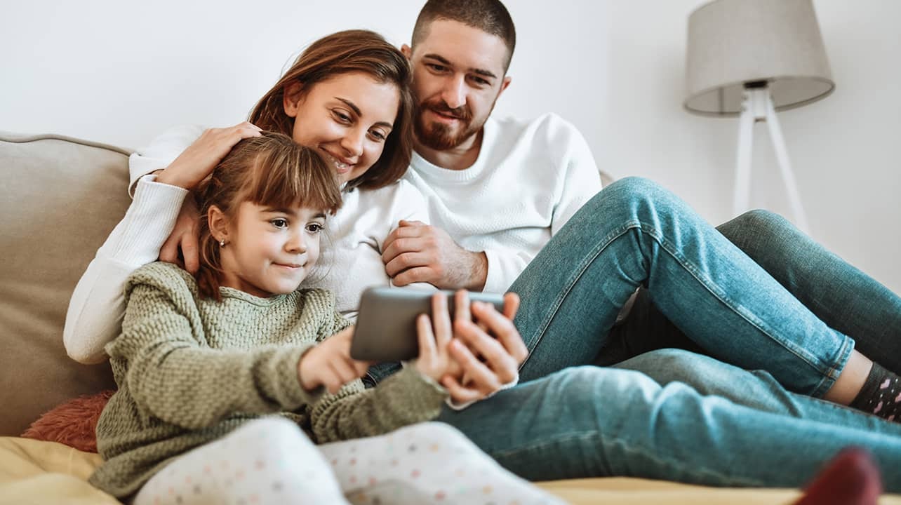 A father, mother and daughter watching a discovery+ show on one smartphone.