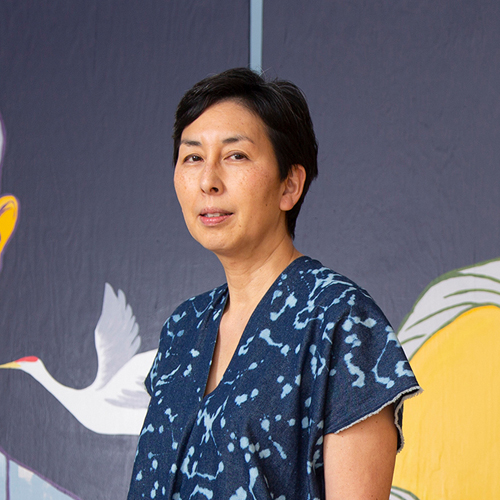 Photograph of an Asian woman whit short black hair wearing a blue shirt.