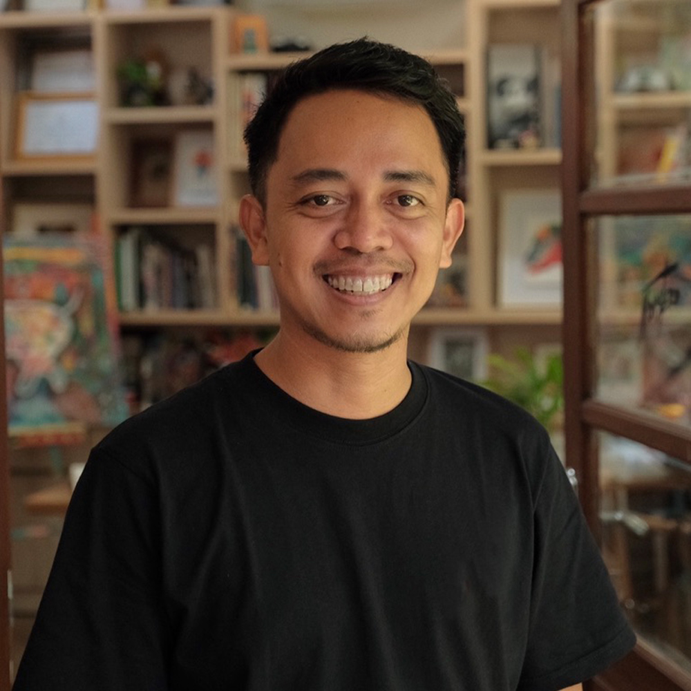 Photo of a man with short black hair and a black shirt smiling