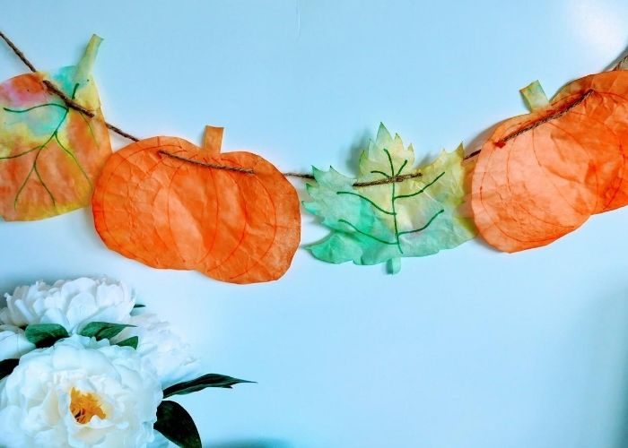 Orange dyed coffee filter cut into a pumpkin on a garland.