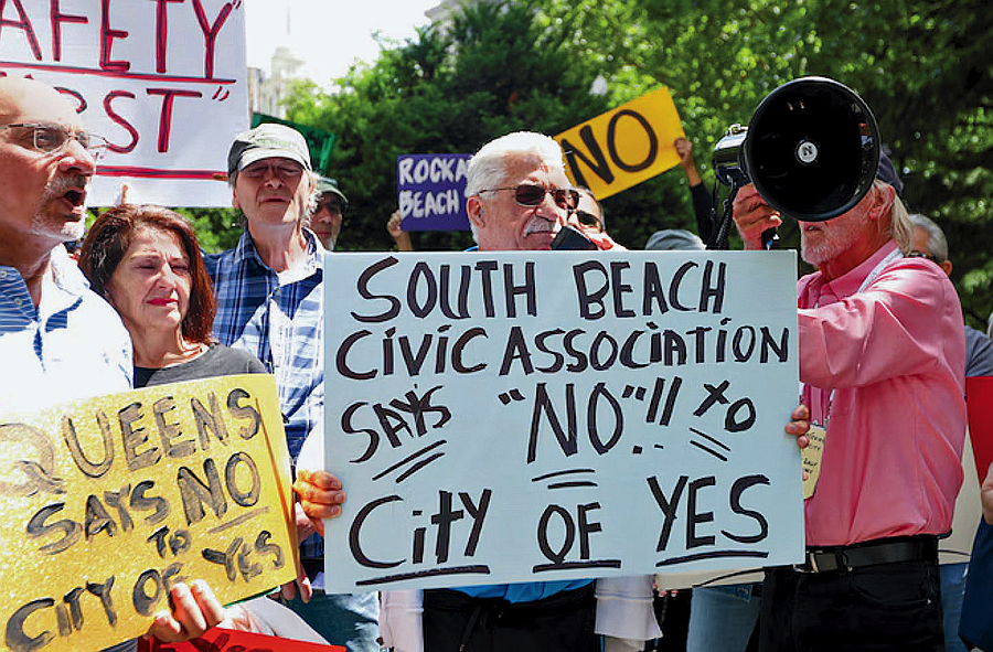 Group of people holding signs protesting a housing initiative.