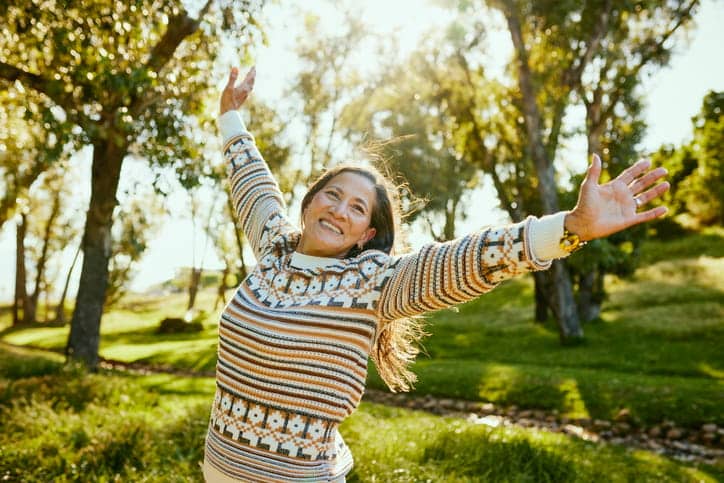 An Elderly Woman With Her Arms Outstretched As She Enjoys The Spring Weather.