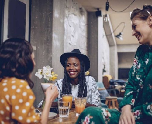 Three women chatting over coffee and juice at a cafe