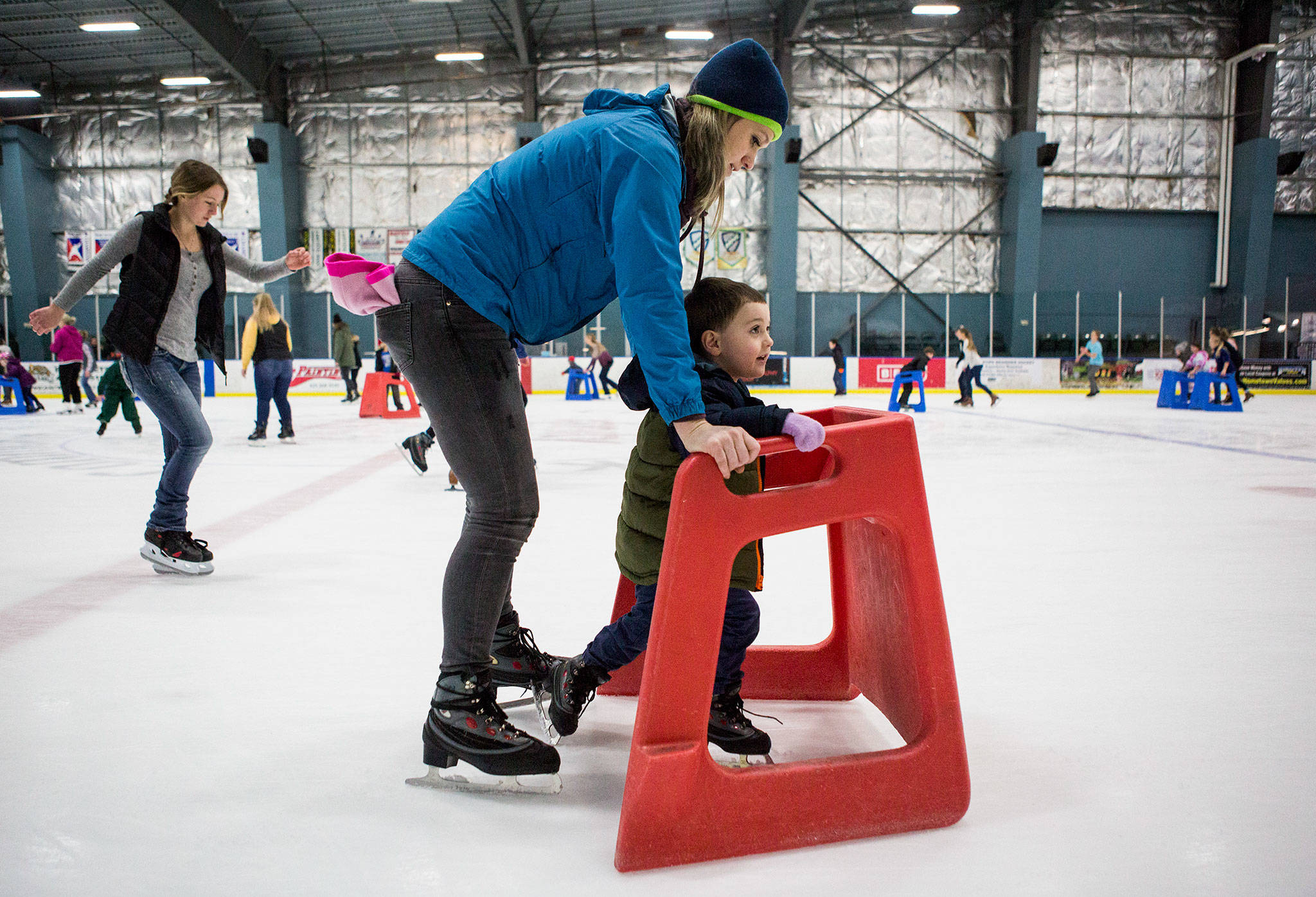 Kellie Alleman helps her son Camden Alleman, 3, as he learns to skate with a walker at the Xfinity Community Ice Rink on Dec. 28 in Everett. (Olivia Vanni / The Herald)