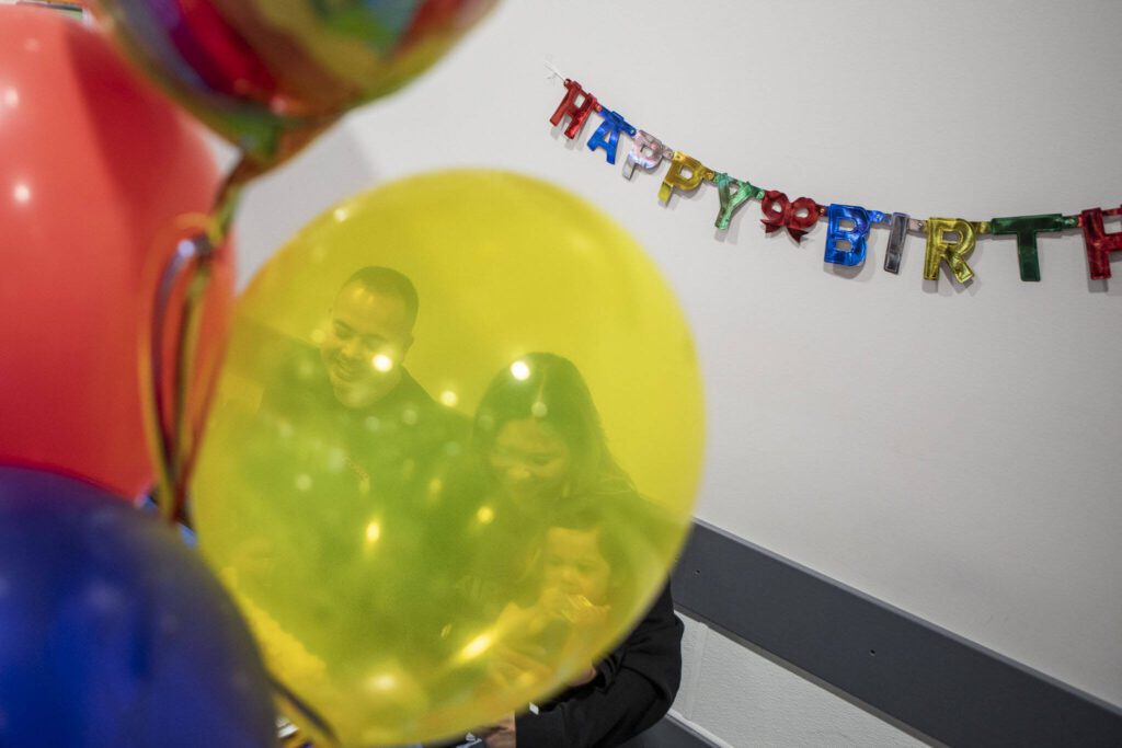 Left to right, Angelo Sarmiento, Jona Sarmiento and Carlisle Sarmiento prepare to cut the cake during a first birthday party at Costco in Lake Stevens on Friday, May 31, 2024. (Annie Barker / The Herald)
