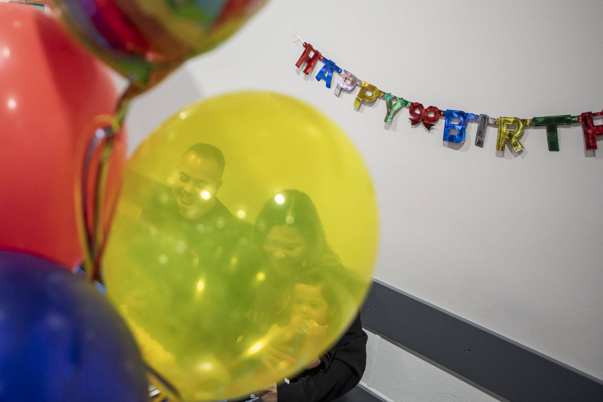 Left to right, Angelo Sarmiento, Jona Sarmiento, and Carlisle Sarmiento prepare to cut the cake during a first birthday party at Costco in Lake Stevens, Washington on Friday, May 31, 2024. Jona’s water broke in the store a year ago (Annie Barker / The Herald)