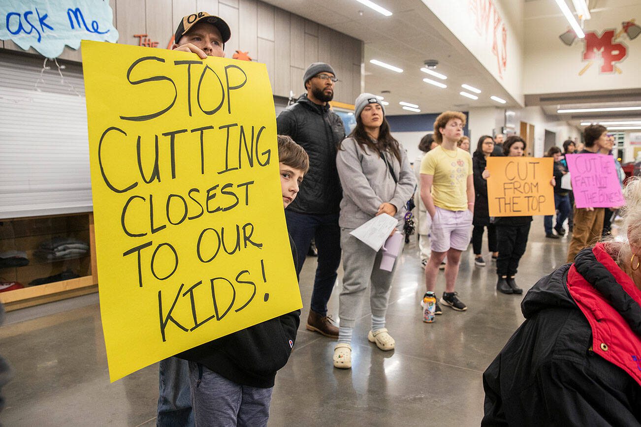 Grayson Huff, left, a 4th grader at Pinewood Elementary, peeks around his sign during the Marysville School District budget presentation on Tuesday, Nov. 28, 2023 in Marysville, Washington. (Olivia Vanni / The Herald)