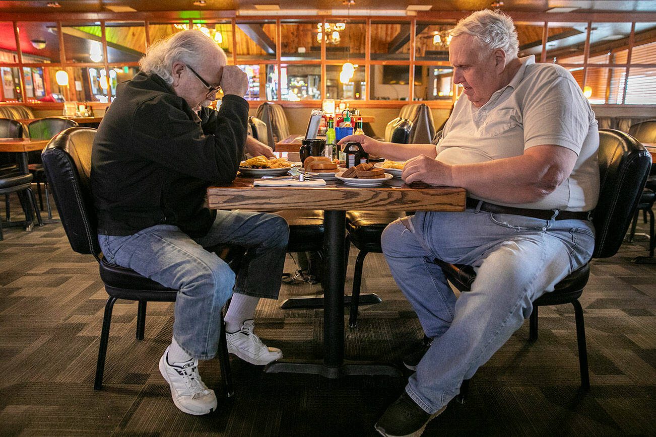 Paul Pollard, 71, left, leads a prayer before himself and James Mock, 67, eat their lunch at Buzz Inn Steakhouse on Tuesday, Dec. 3, 2024 in Everett, Washington. (Olivia Vanni / The Herald)