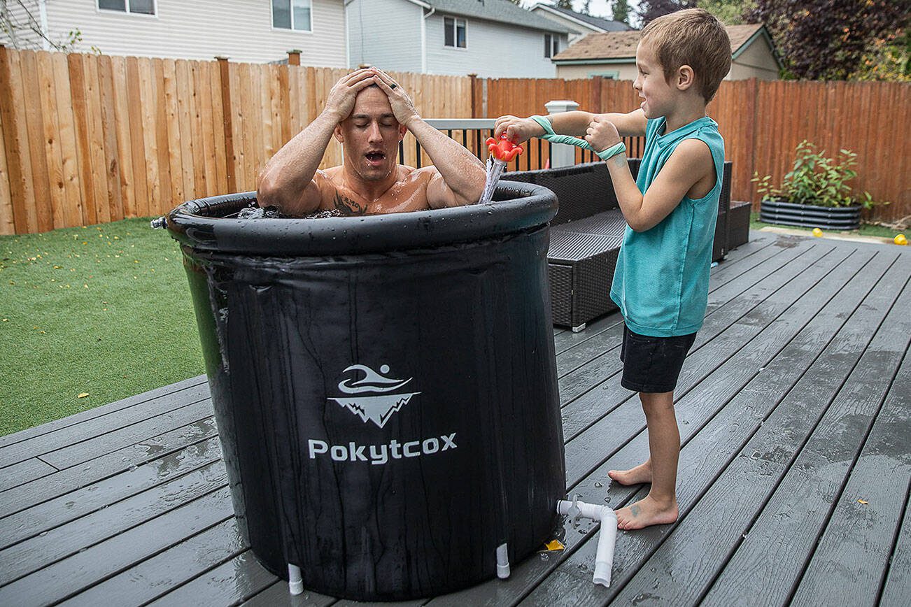 Jared Meads takes a breath after dunking in an ice bath in his back yard while his son Fallen, 5, reads off the water temperature on Tuesday, Oct. 15, 2024 in Everett, Washington. (Olivia Vanni / The Herald)