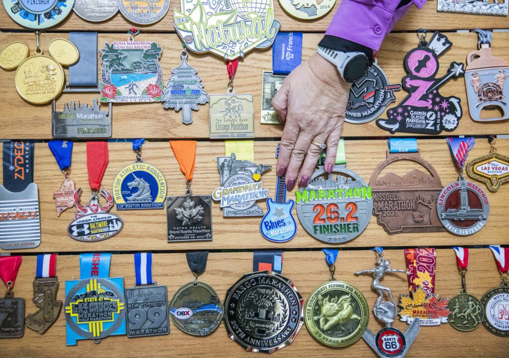 Robin Cain adjusts one of her marathon medals on Thursday, Jan. 2, 2025 in Lake Stevens, Washington. (Olivia Vanni / The Herald)
