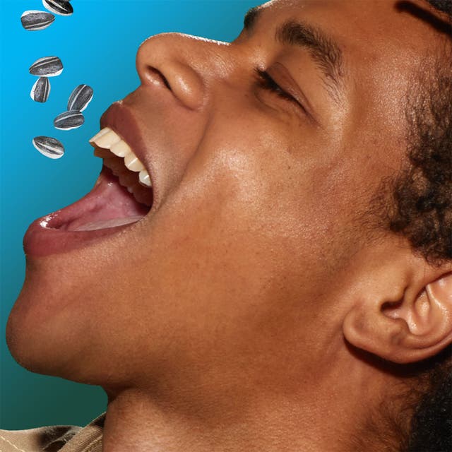 man pouring sunflower seeds into his mouth