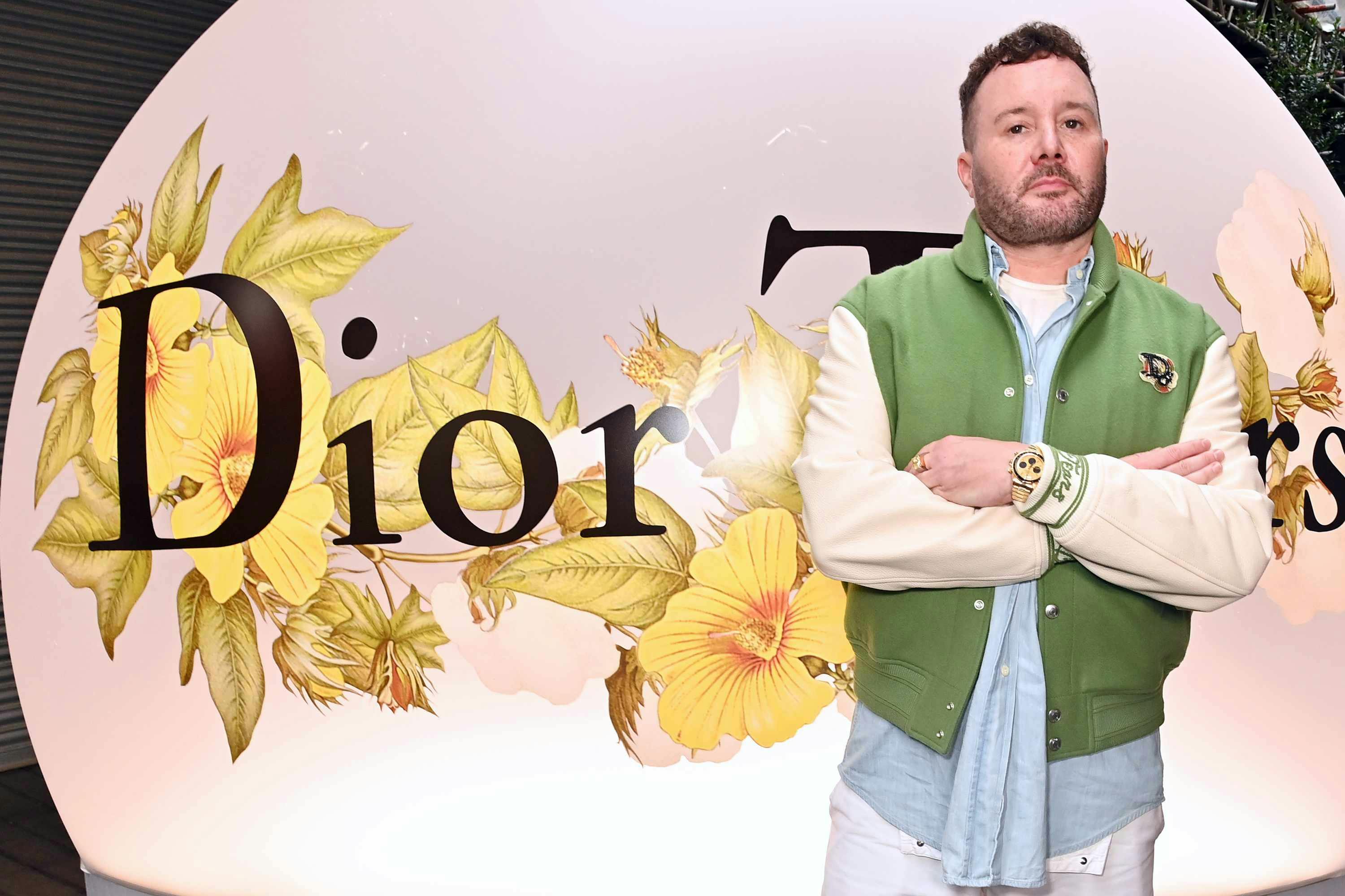 Kim Jones wears a green varsity jacket and blue denim shirt at the Dior Tears launch party