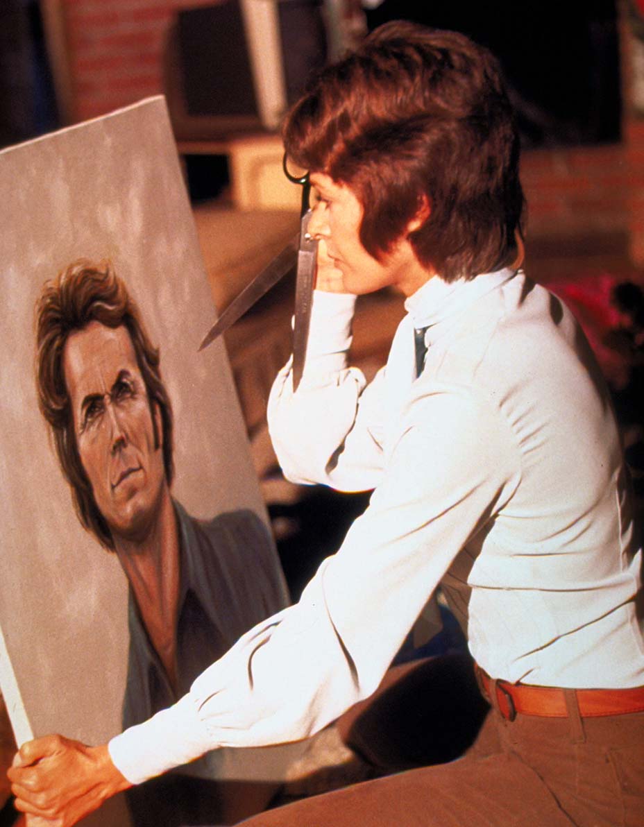 Actress Jessica Walter holding a pair of scissors in front of a colorful painting.