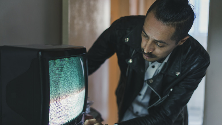 man fusses with old TV