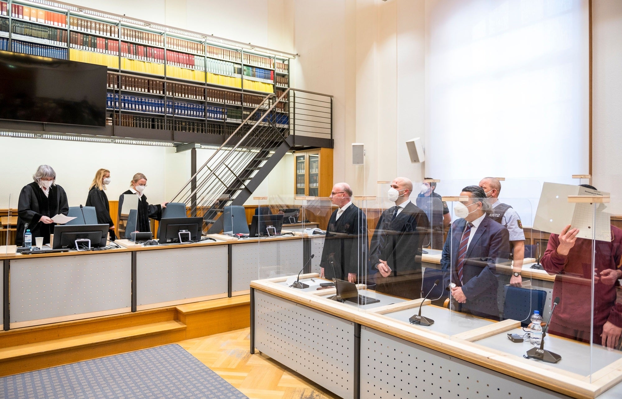 Defendant Eyad A., hidden behind a folder, stands in a Koblenz court on February 24, 2021 to hear the verdict against him for crimes against humanity committed in the Syrian conflict.