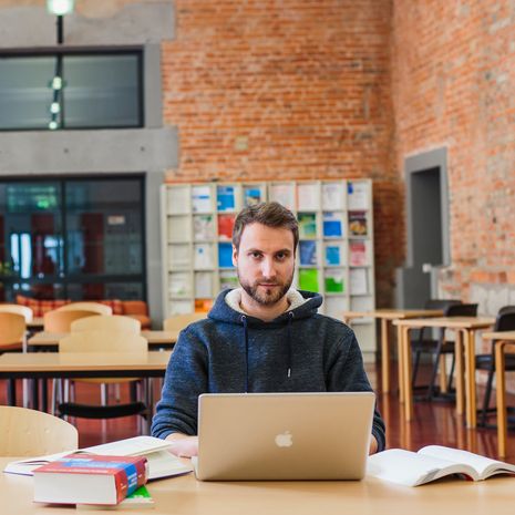 Studierender des Fachbereichs Verwaltungswissenschaften an einem Arbeitsplatz in der Bibliothek.