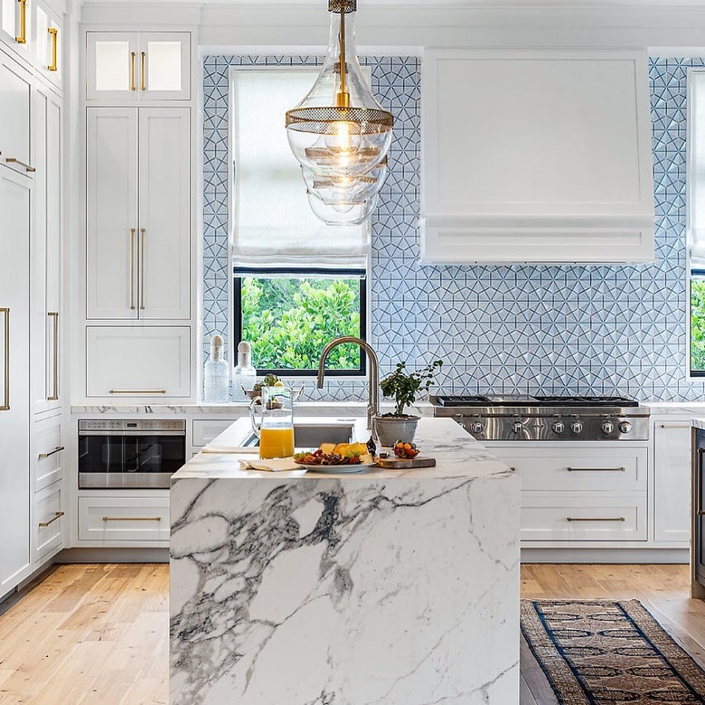 blue tile backsplash modern marble waterfall kitchen with white cabinets and brass hardware