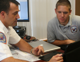 An officer and a firefighter intent on a tablet screen