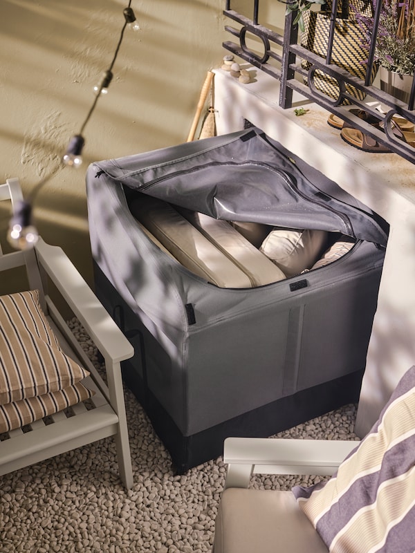 A VÄTTERSÖ outdoor storage box with the zip partially open. Inside there are some FRÖSÖN/DUVHOLMEN back cushions in beige.