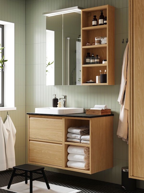 A bathroom with an oak effect/white marble effect BACKSJÖN wash-stand/wash-basin/tap.