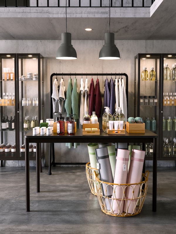 A TOMMARYD table in front of two MILSBO anthracite glass cabinets and a basket of yoga mats on the floor.