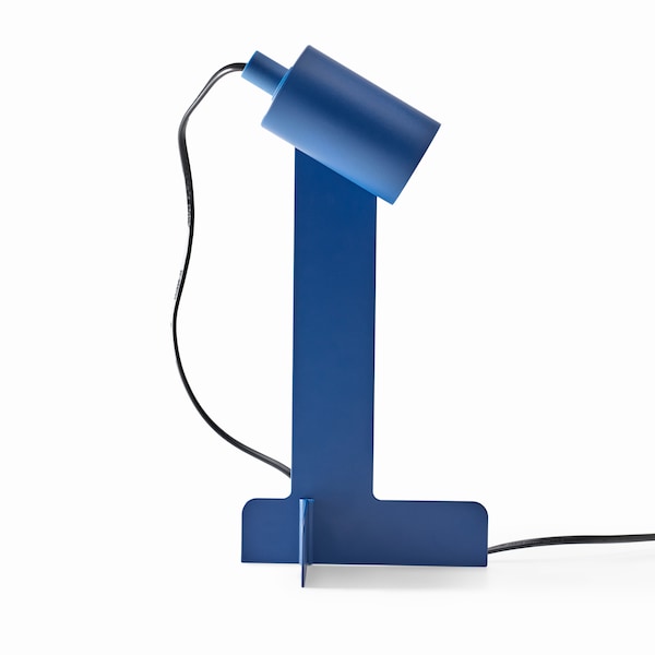 A side view of a blue FLOTTILJ desk lamp with the swivel head directed downwards.