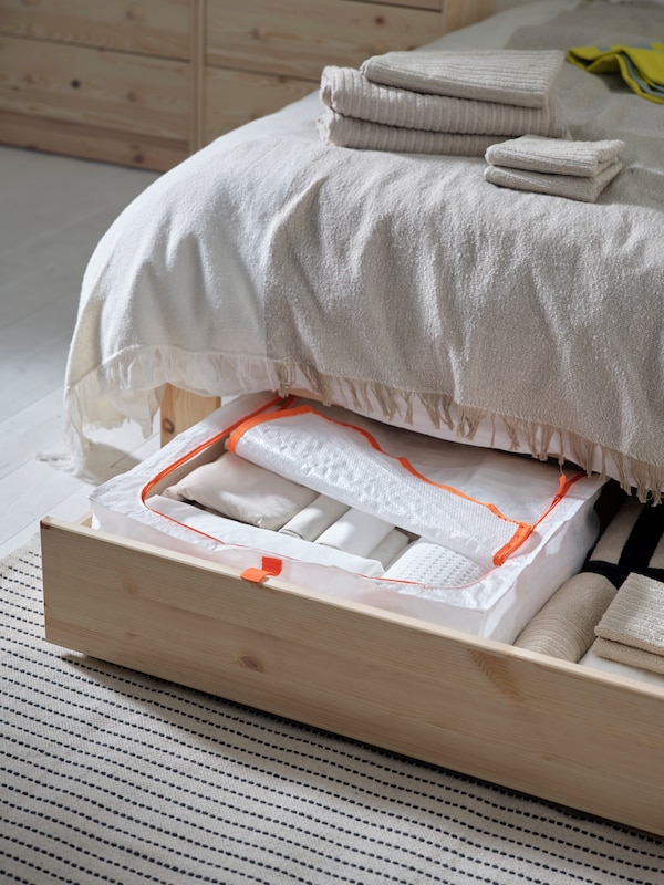 An extended drawer of a GLAMBERGET extendable bed with storage in pine with a PÄRKLA storage case in it.