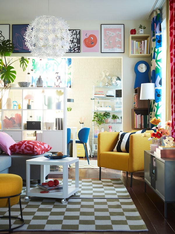 A vibrant living room with KLASSRUM rugs, an ÄLVDALEN sofa-bed, a TINGBY side table, an EKERÖ armchair and ample decoration.