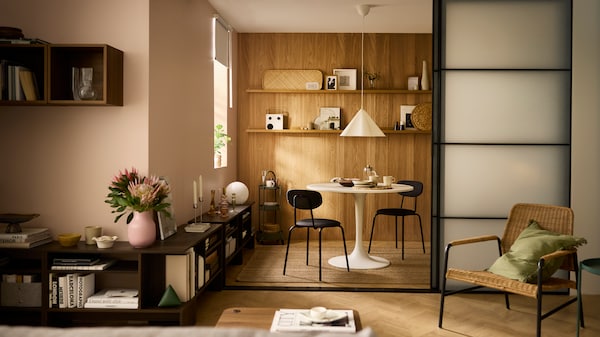 Part of a living room opening up, by way of SKYTTA sliding doors, onto a dining area with a white, round DOCKSTA table.