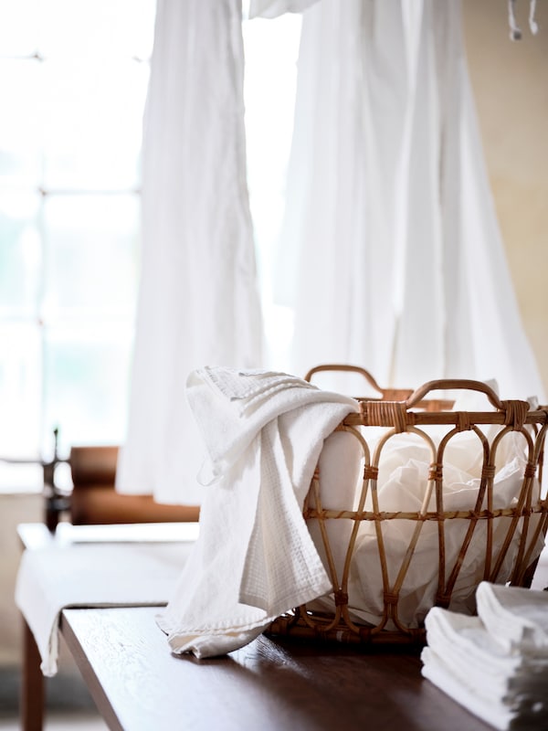 A half-full SNIDAD laundry basket in the middle of a brown wooden table.