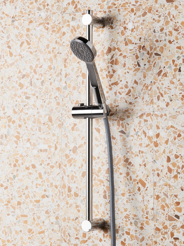 A shower wall with a VALLAMOSSE riser rail with hand-shower kit holding a chrome plated VALLAMOSSE thermo shower mixer.