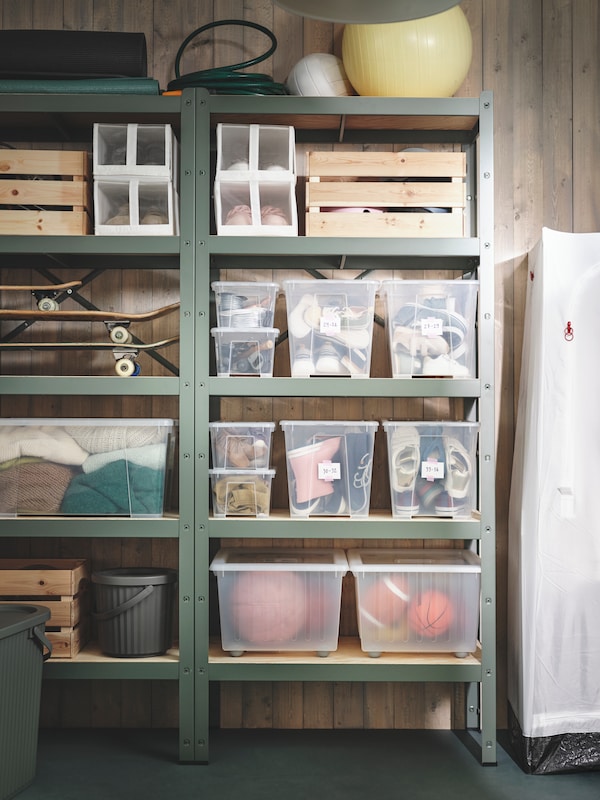 A BROR shelving unit in a garage, filled with wooden crates, clear plastic boxes, and bins. 