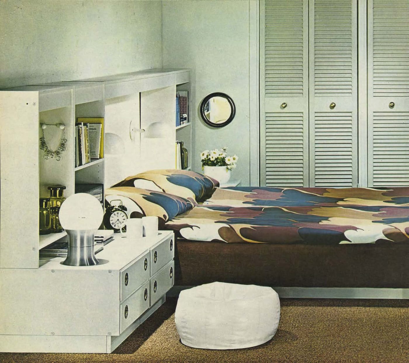 A white bedroom from the 1971 IKEA catalogue featuring a white headboard unit with a bed with brown patterned bedlinen.