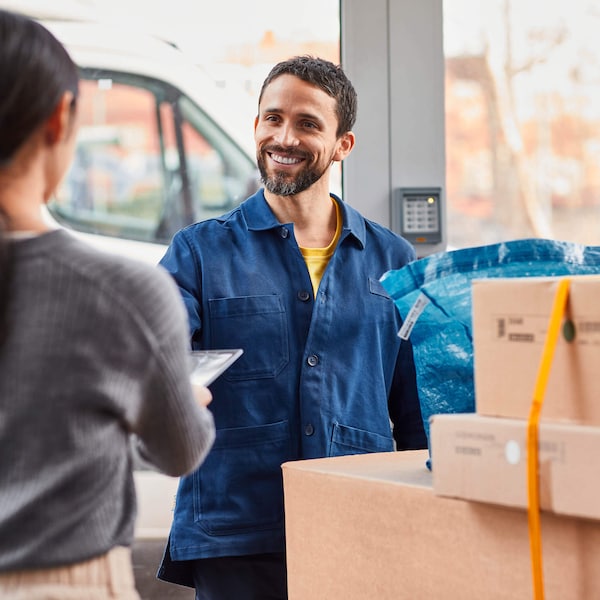 A delivery man smiling at a customer and delivering IKEA boxes.