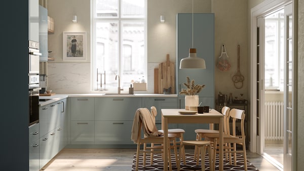 A kitchen with KALLARP kitchen fronts, a RÖNNINGE table with four chairs and a BUNKEFLO pendant lamp in white and birch.