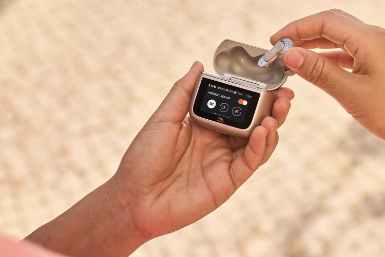 JBL Tour Pro 3 earbuds, held in a hand with a focus on the smart charging case