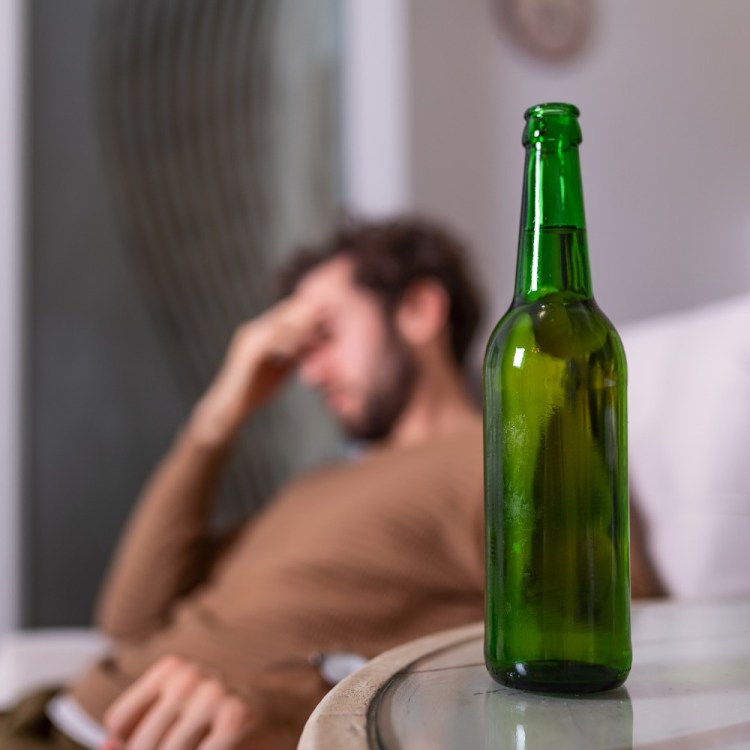 Man slumped behind beer bottle