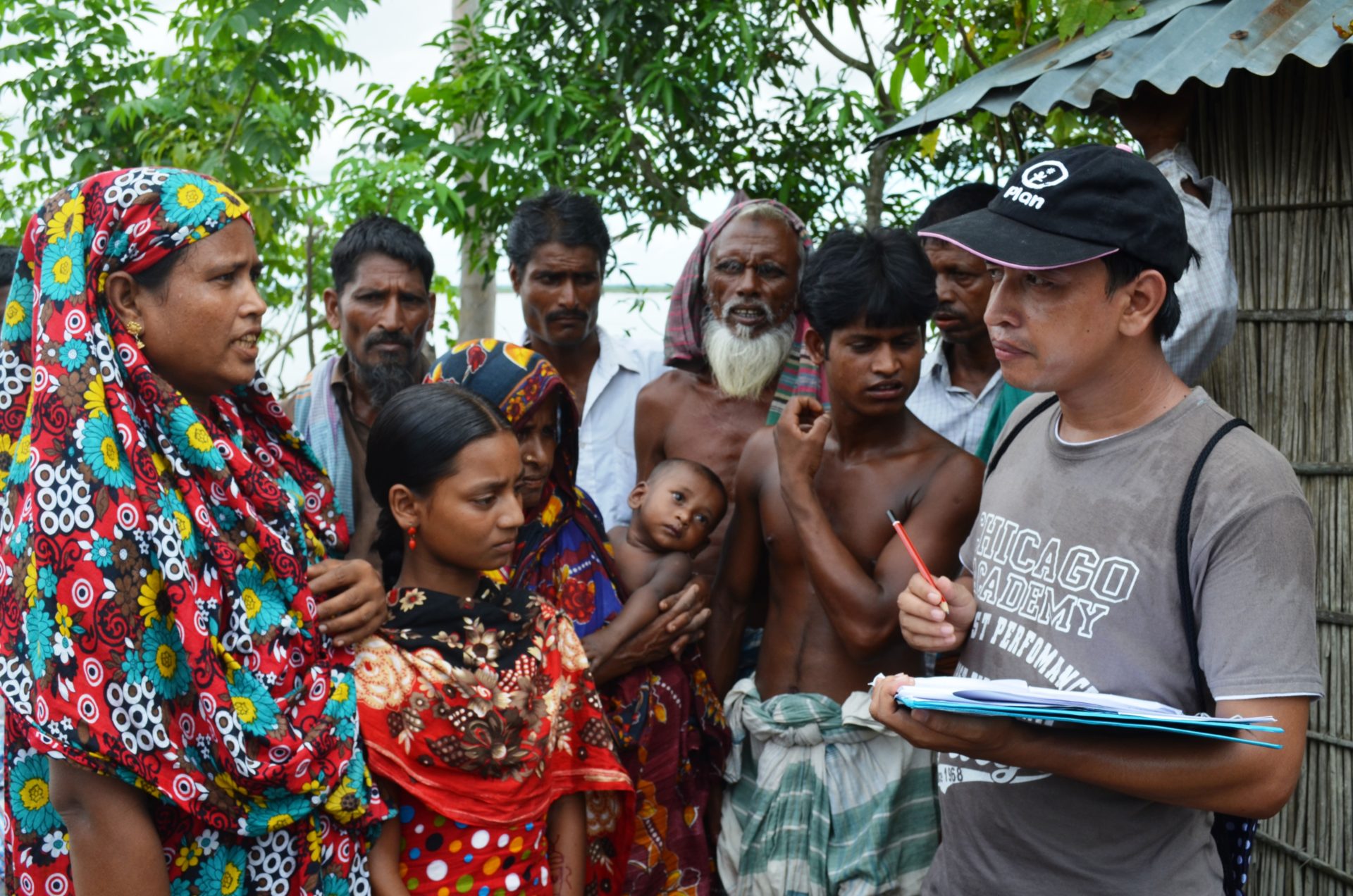 A man interviews a group of people, taking notes on a clipboard