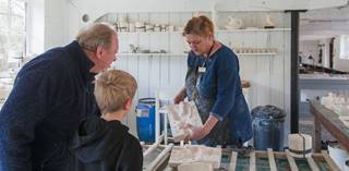 A demonstrator holds up a slip casting mould for a pair of visitors to see, in the long workshop, Coalport China Museum.