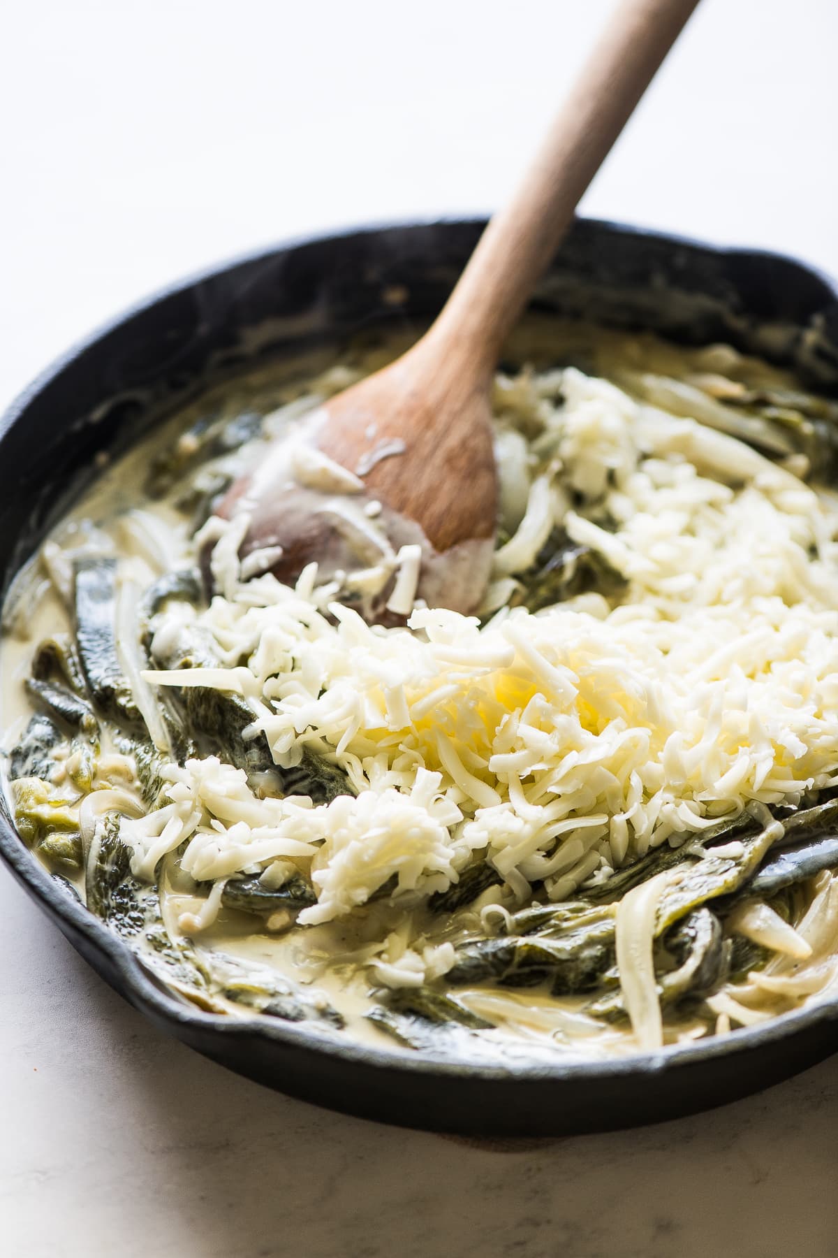 Queijo de Oaxaca desfiado a ser mexido em frigideira de rajas com crema.