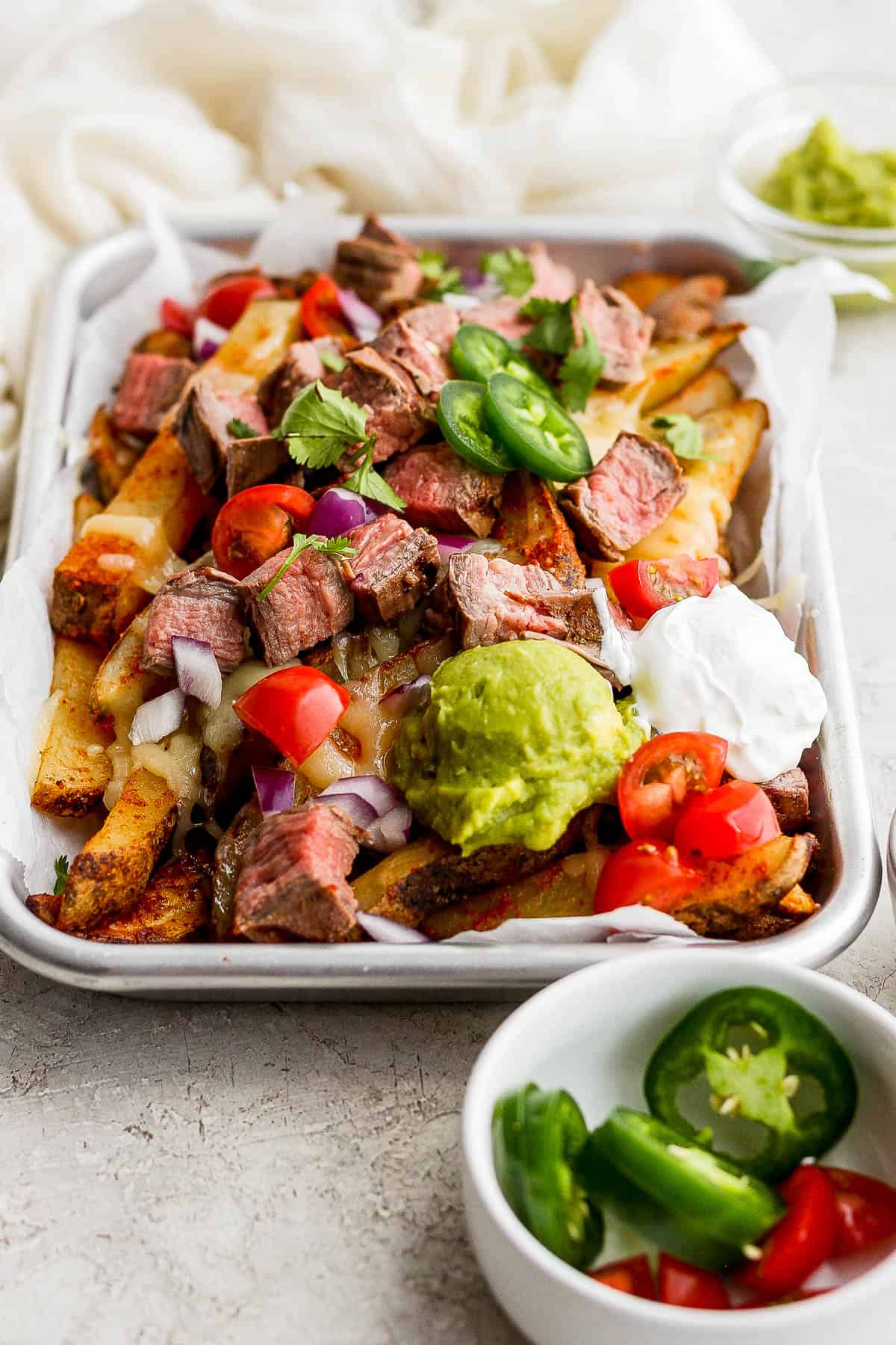 Carne asada fries plated with all the toppings and ready to eat